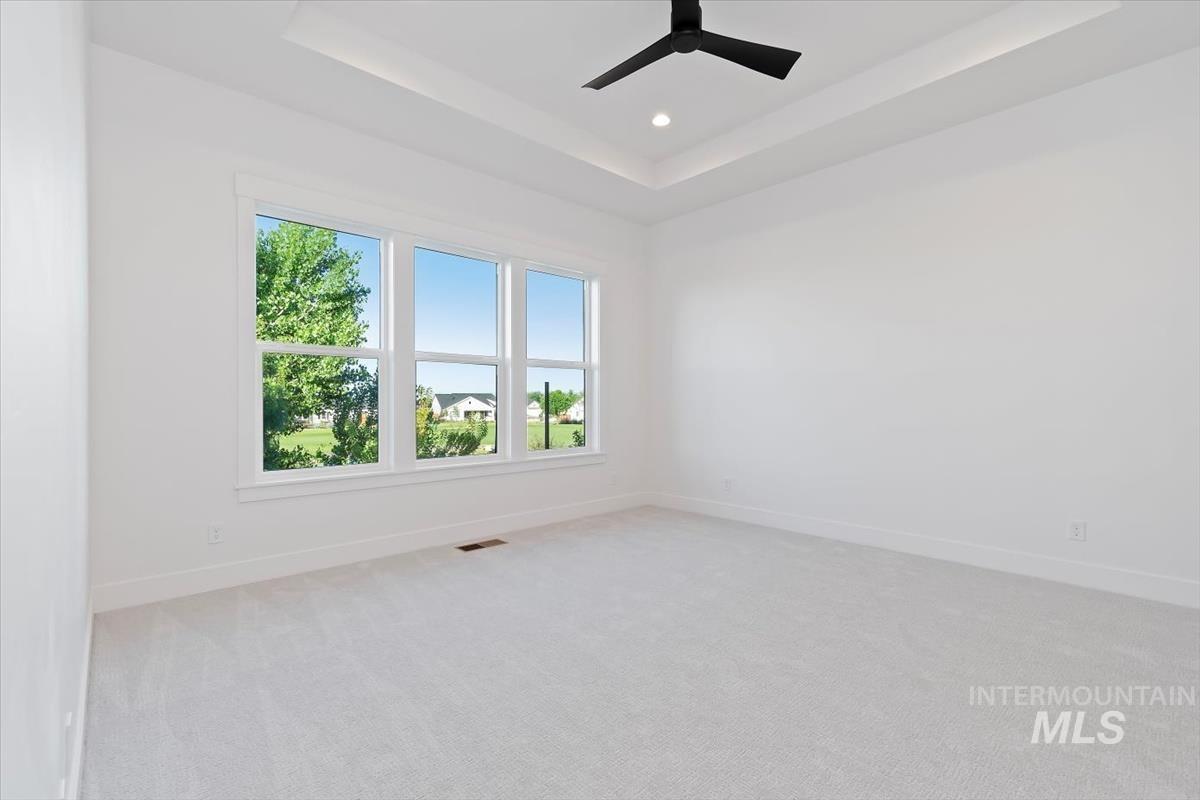 Unfurnished room featuring a tray ceiling, light carpet, recessed lighting, and a ceiling fan
