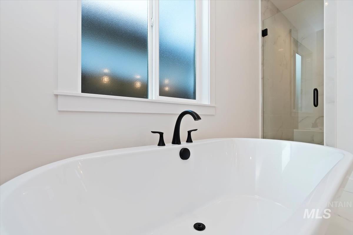 Bathroom featuring a freestanding bath and a marble finish shower