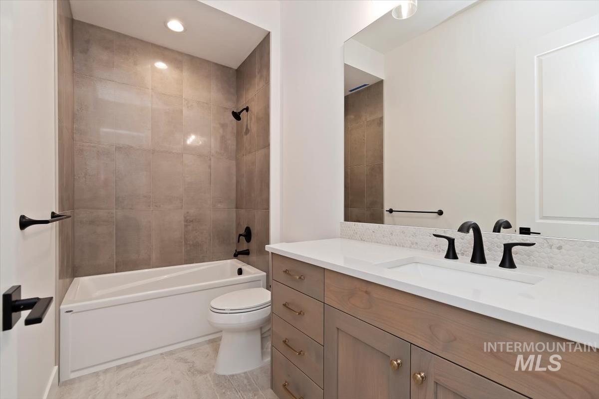 Bathroom featuring washtub / shower combination, vanity, and recessed lighting