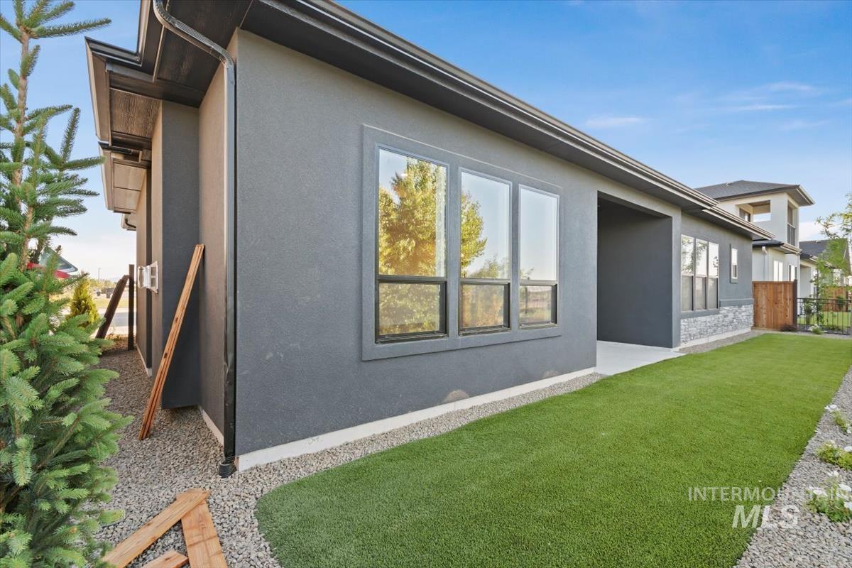 View of side of home featuring stucco siding, a patio area, and stone siding