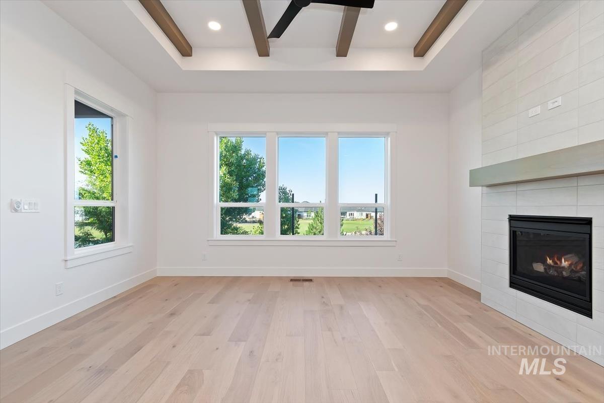 Unfurnished living room featuring light wood finished floors, a fireplace, beam ceiling, recessed lighting, and a ceiling fan