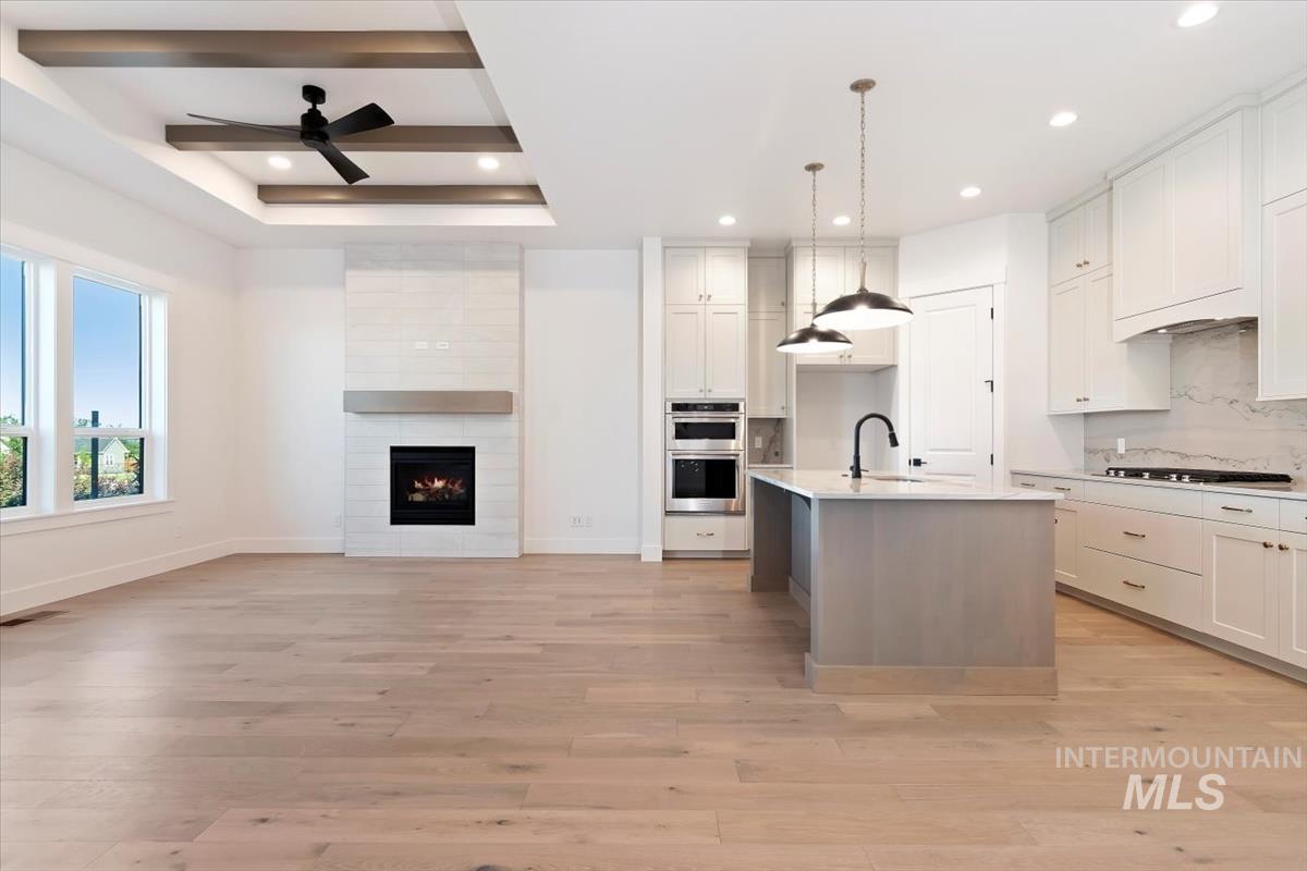 Kitchen with white cabinetry, an island with sink, open floor plan, and recessed lighting