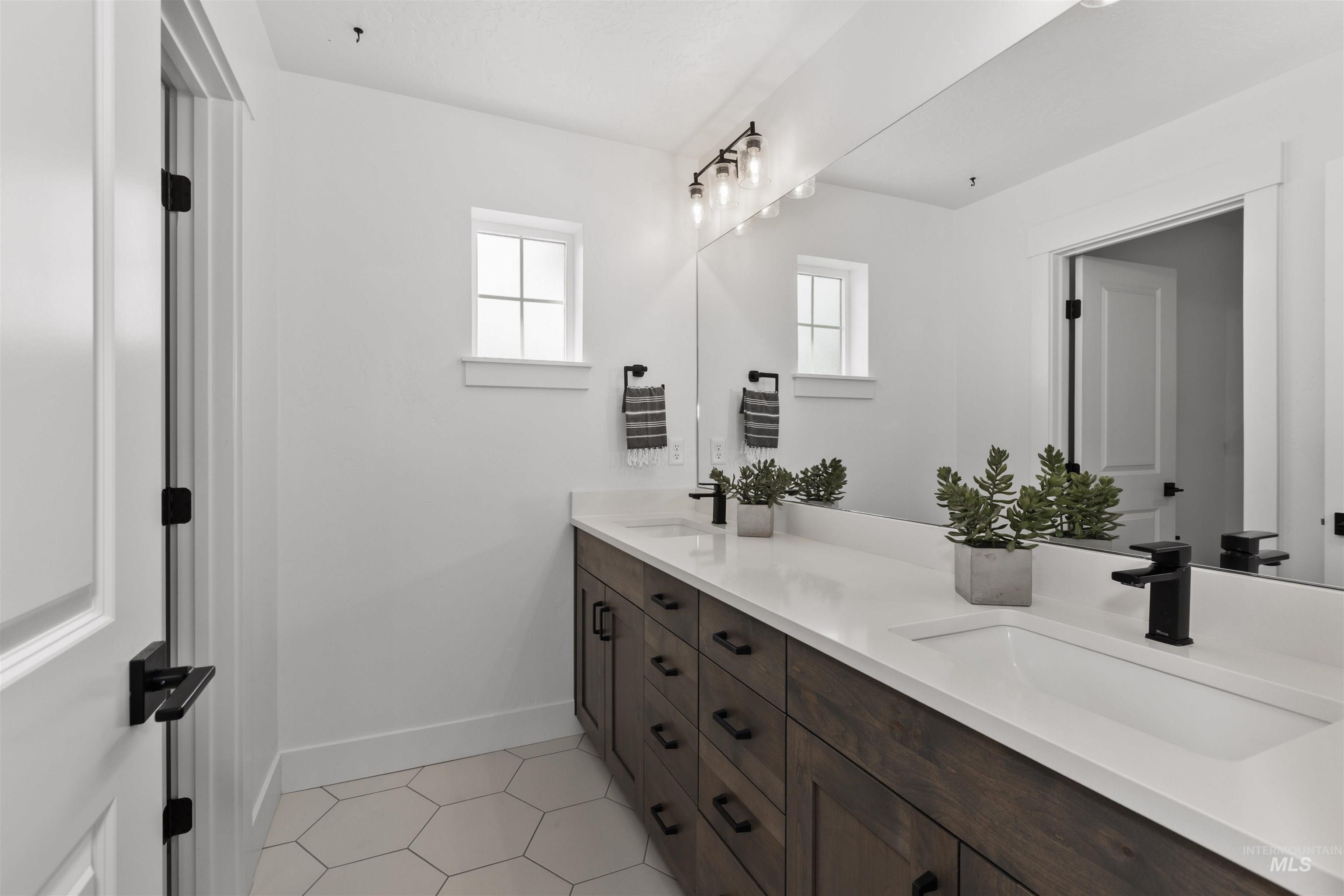 Full bath with double vanity and light tile patterned flooring