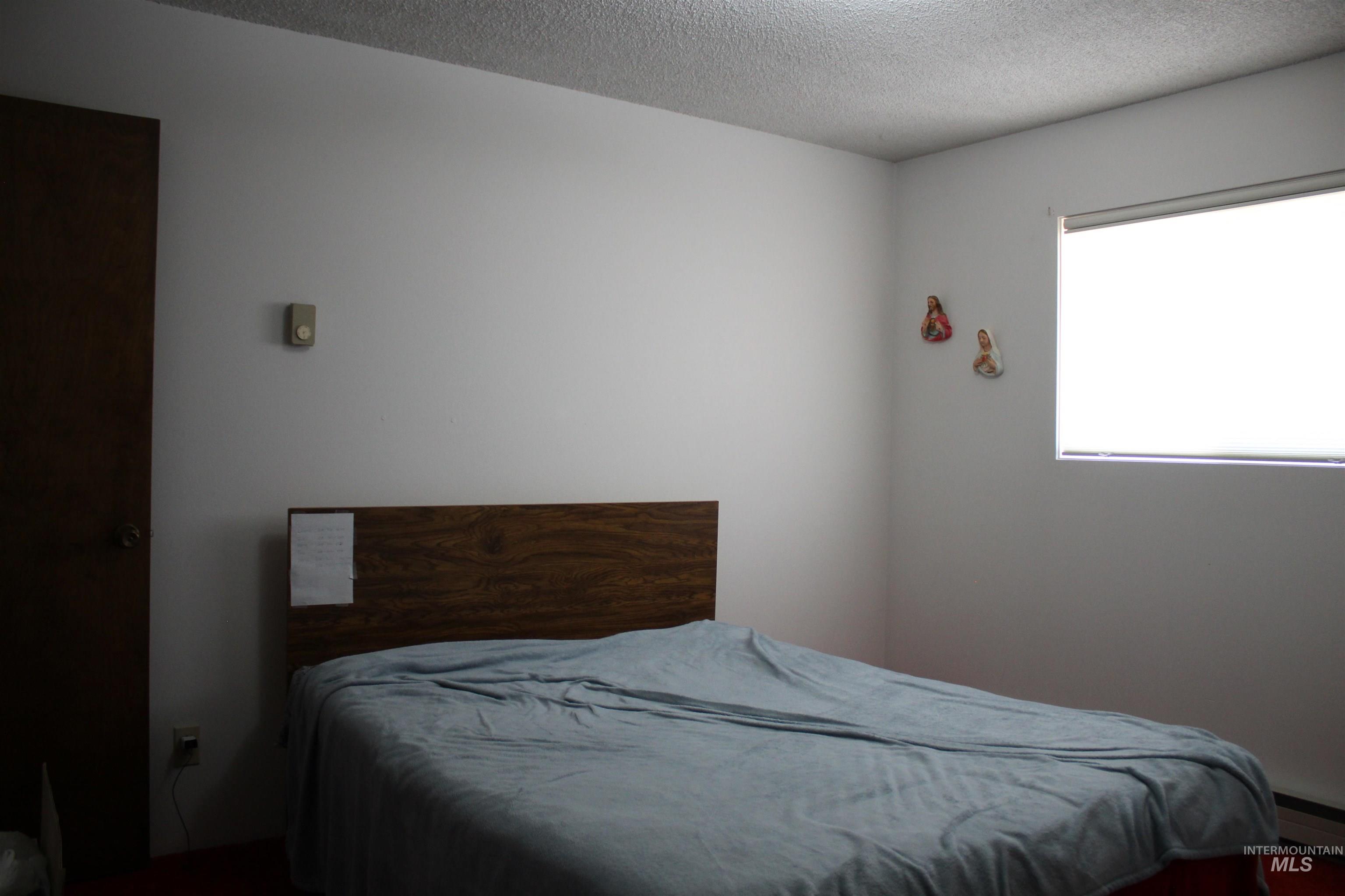 Bedroom featuring a baseboard radiator and a textured ceiling