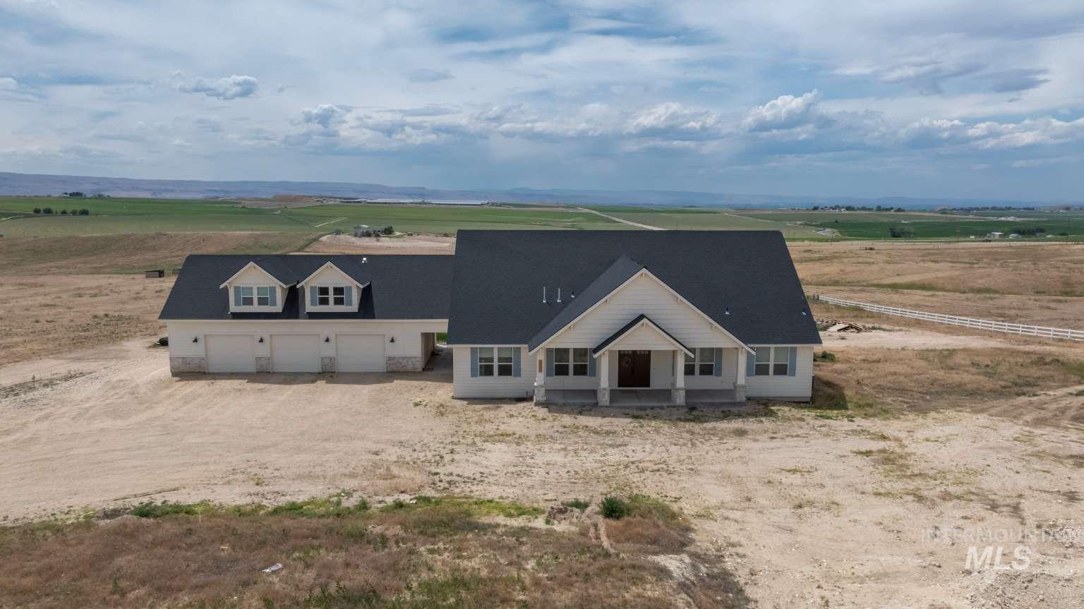 View of front facade featuring a view of countryside, dirt driveway, and a garage