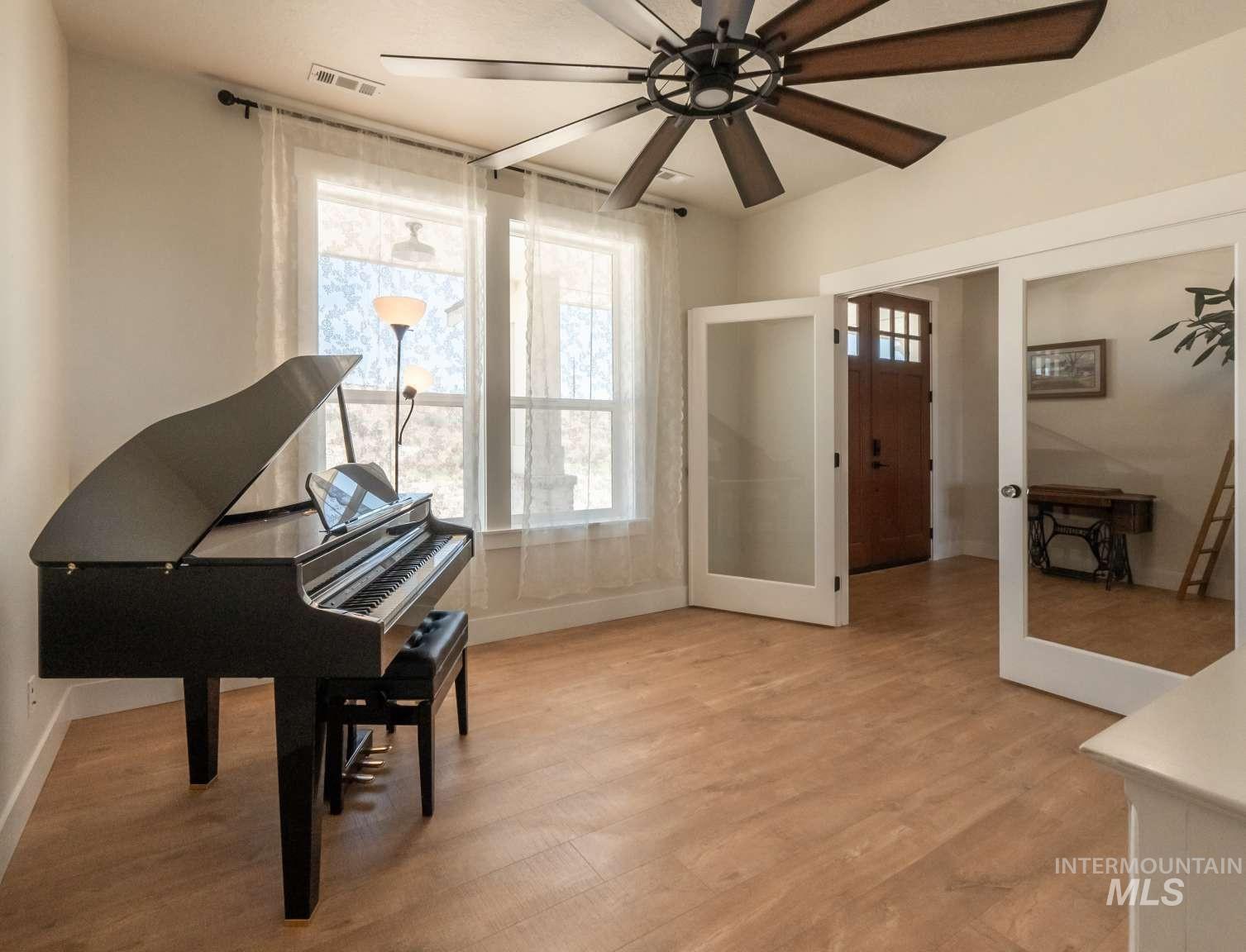 Living area featuring light wood-type flooring, a ceiling fan, and french doors