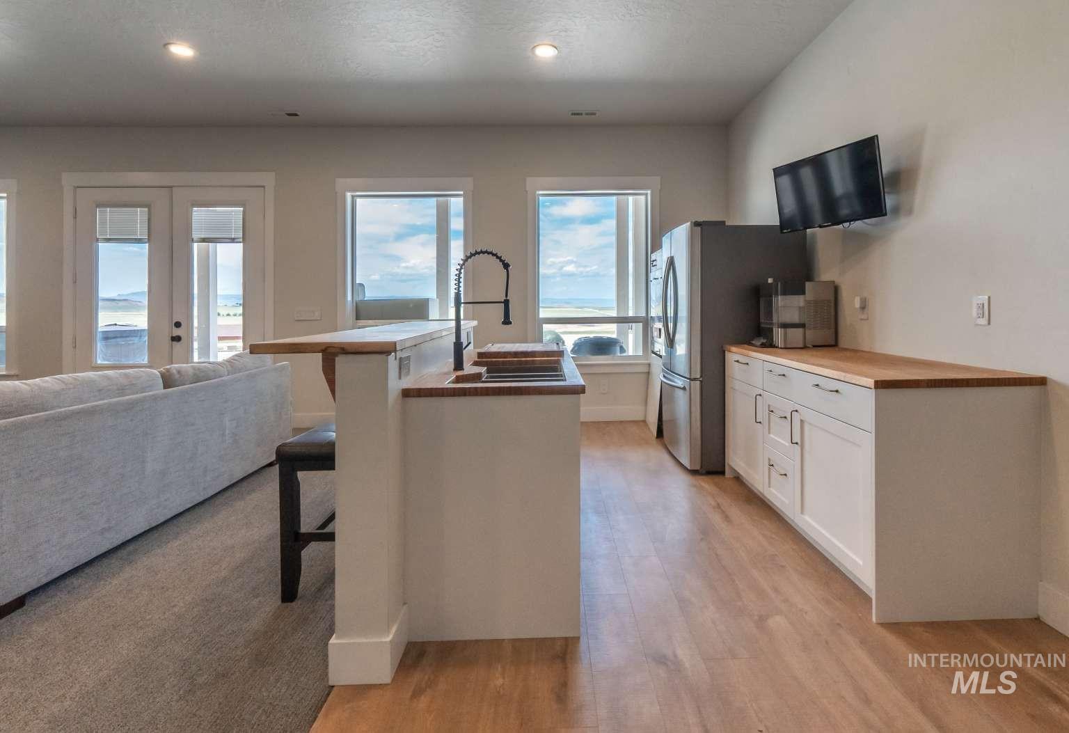 Kitchen featuring white cabinets, wood counters, a breakfast bar, a kitchen island with sink, and open floor plan