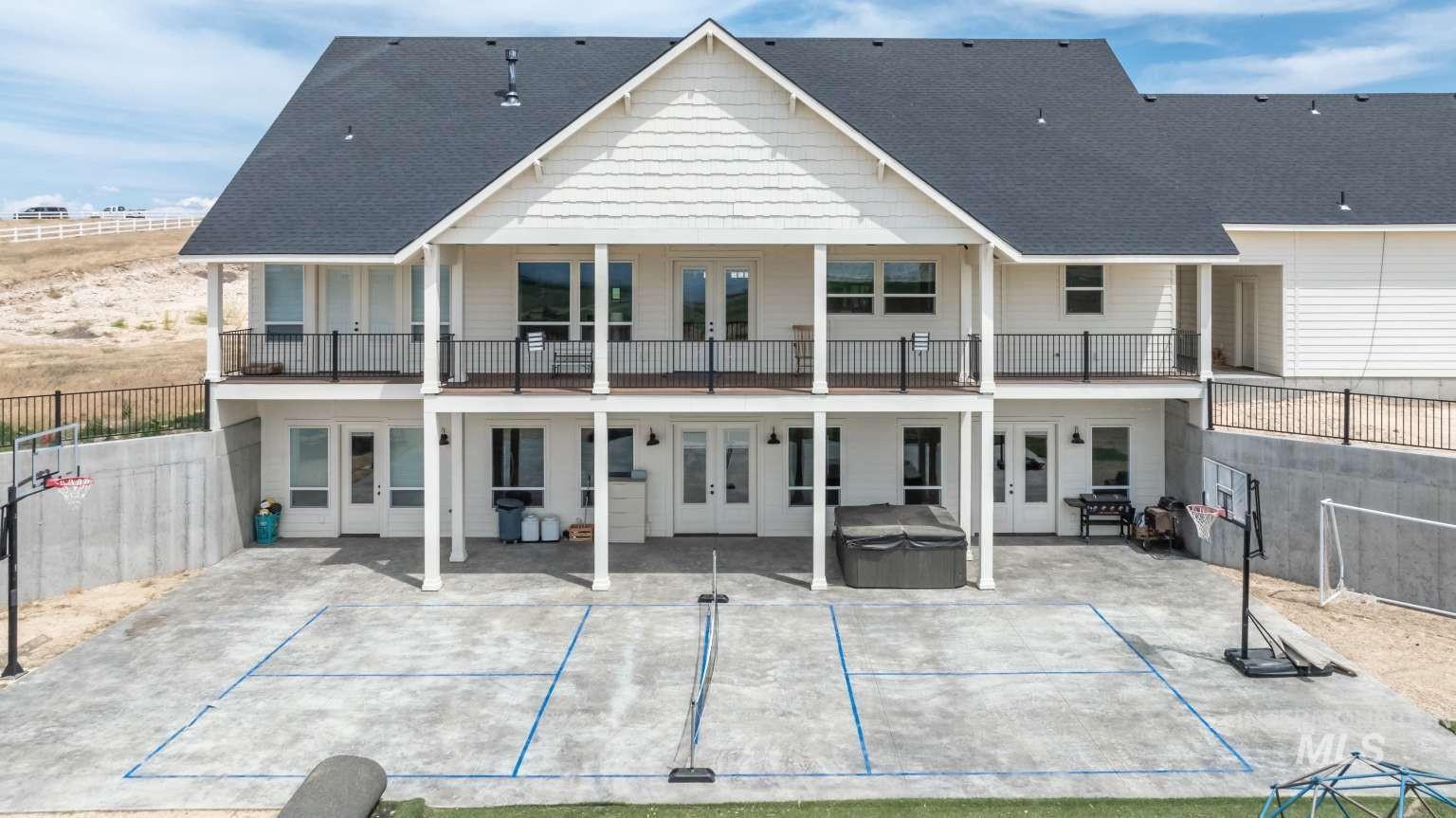 Back of property featuring a hot tub, french doors, a patio area, and roof with shingles
