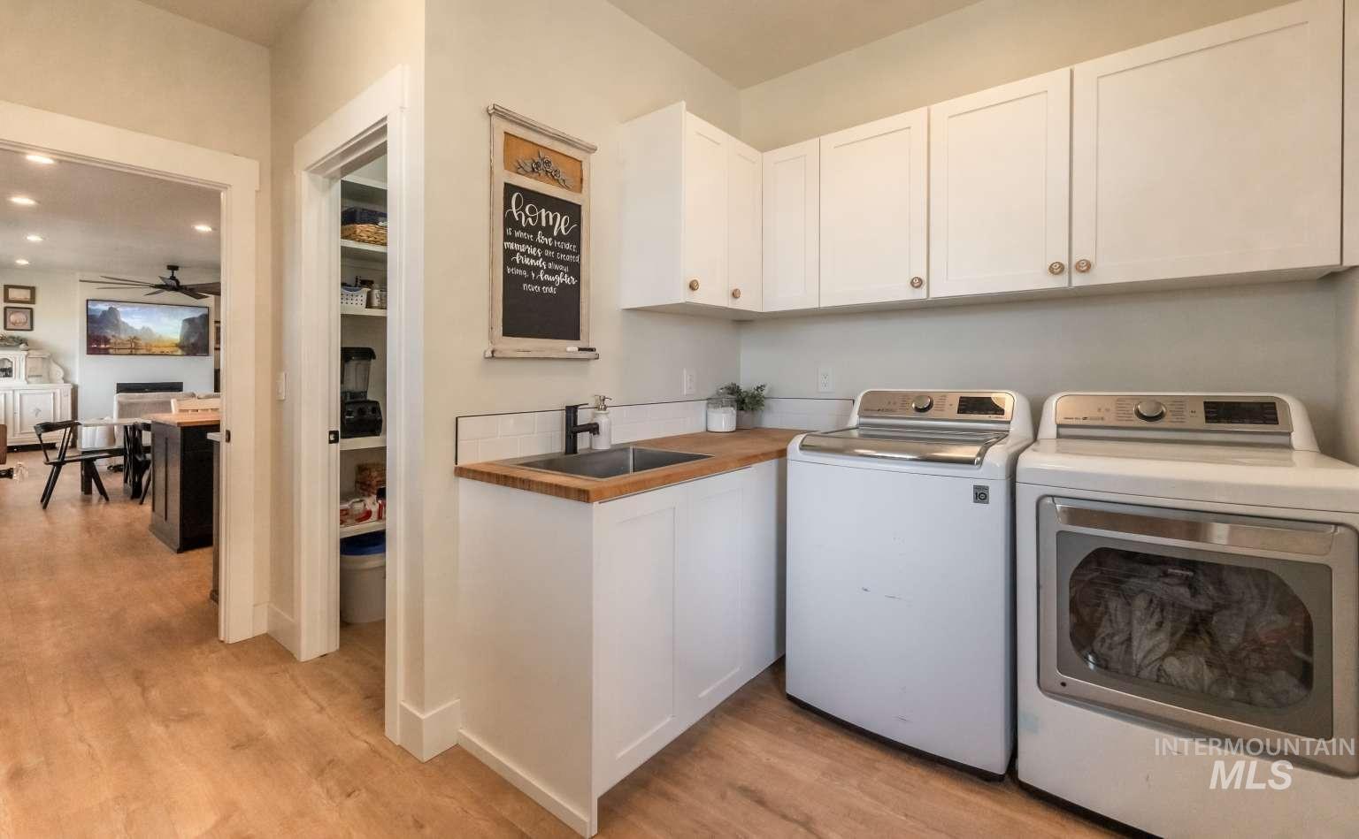 Laundry room with washer and clothes dryer, light wood-style flooring, cabinet space, and a ceiling fan