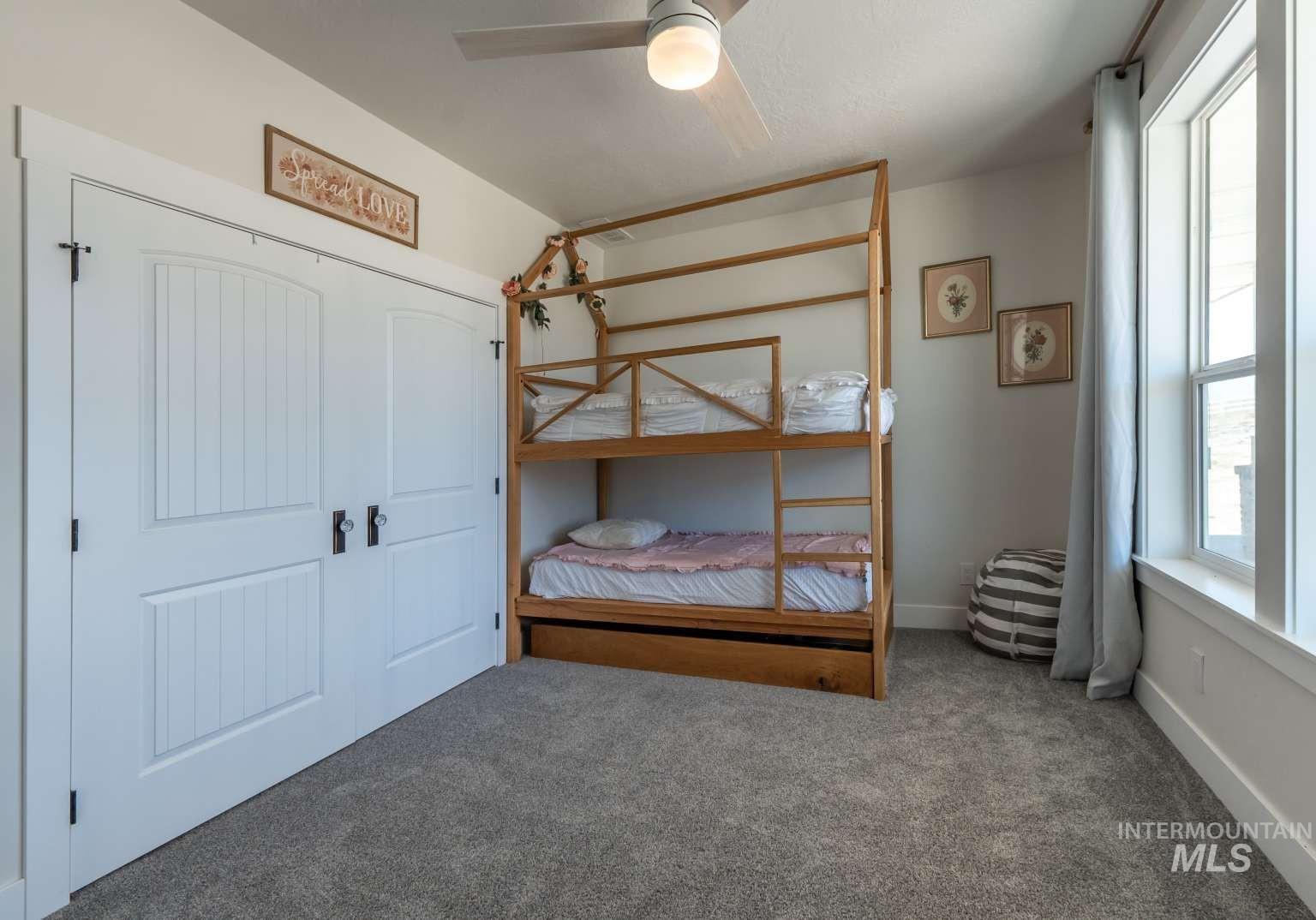 Carpeted bedroom with a ceiling fan and a closet
