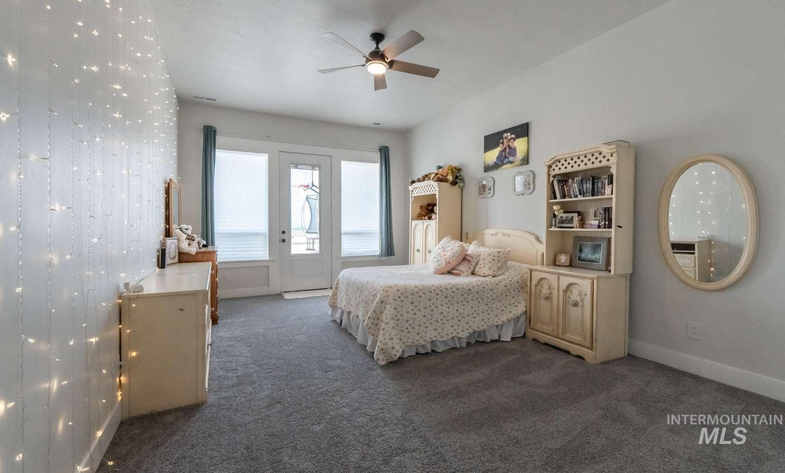 Bedroom with access to exterior, dark carpet, and ceiling fan