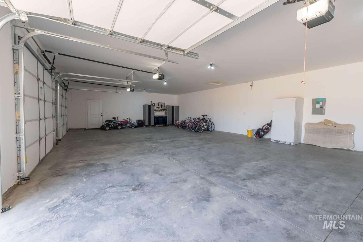Garage featuring freestanding refrigerator, a garage door opener, and electric panel