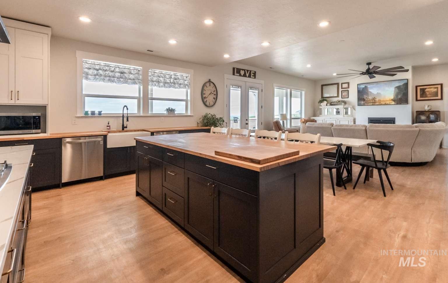 Kitchen with dark cabinetry, a fireplace, stainless steel appliances, wooden counters, and a kitchen island