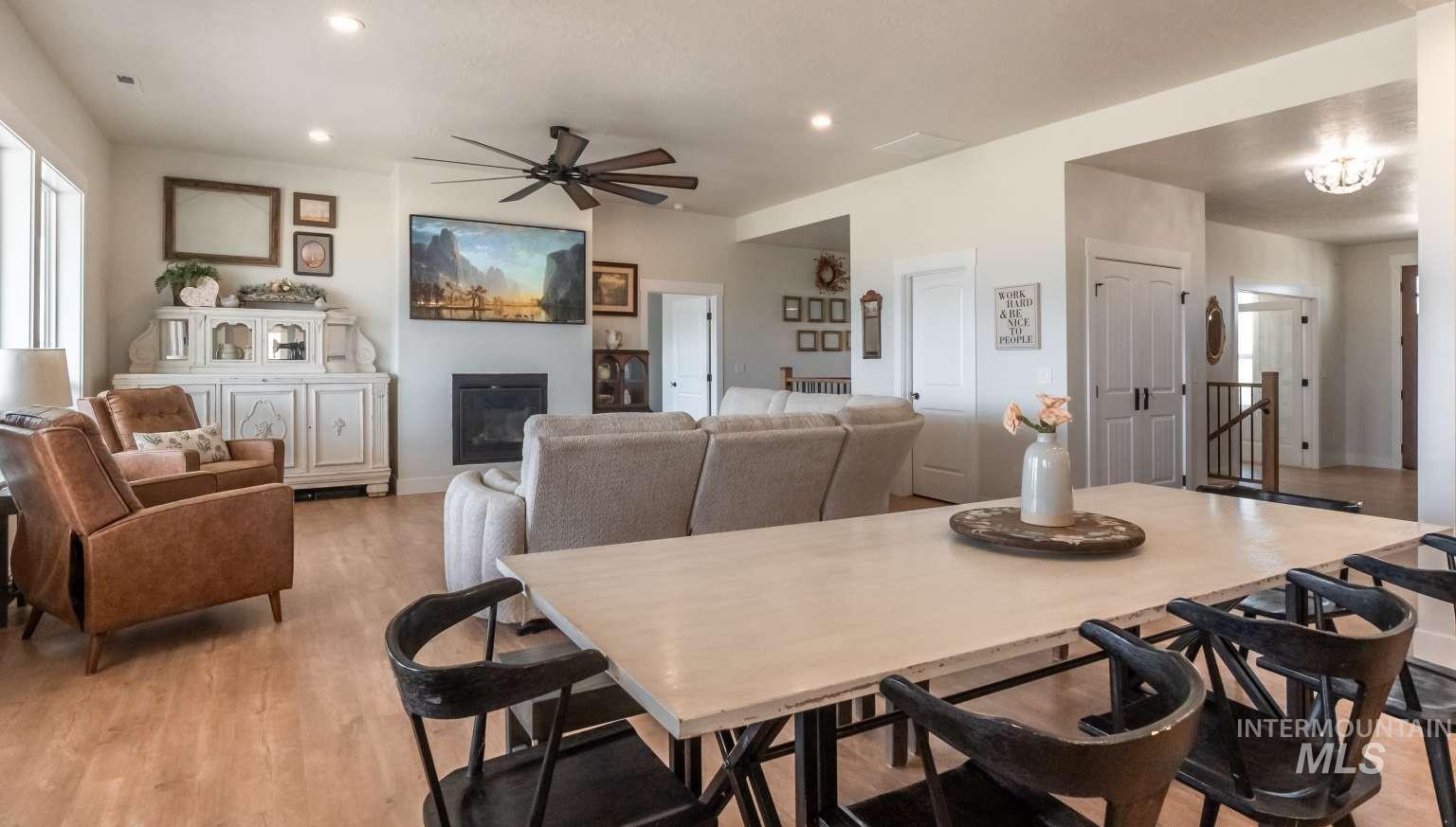 Dining area with a glass covered fireplace, a ceiling fan, light wood finished floors, and recessed lighting