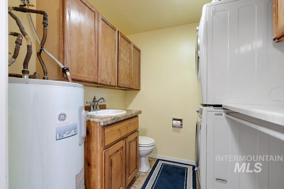Bathroom featuring electric water heater, estacked washer and dryer, and vanity