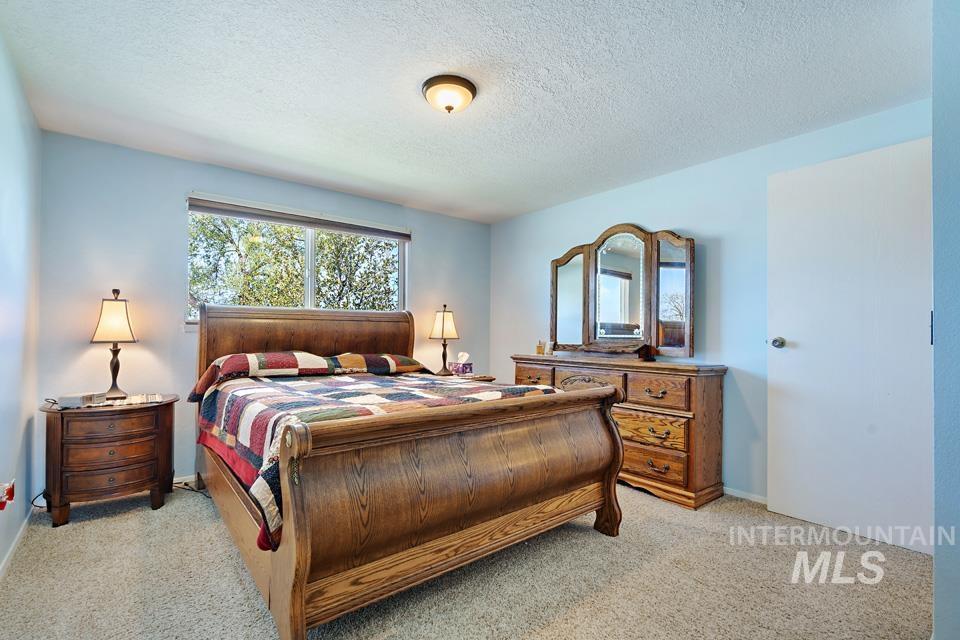 Bedroom with light colored carpet and a textured ceiling