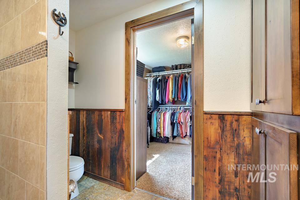 Bathroom with a wainscoted wall, wooden walls, and a walk in closet