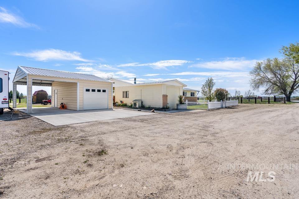 View of side of property featuring an outbuilding, driveway, a metal roof, and a detached garage