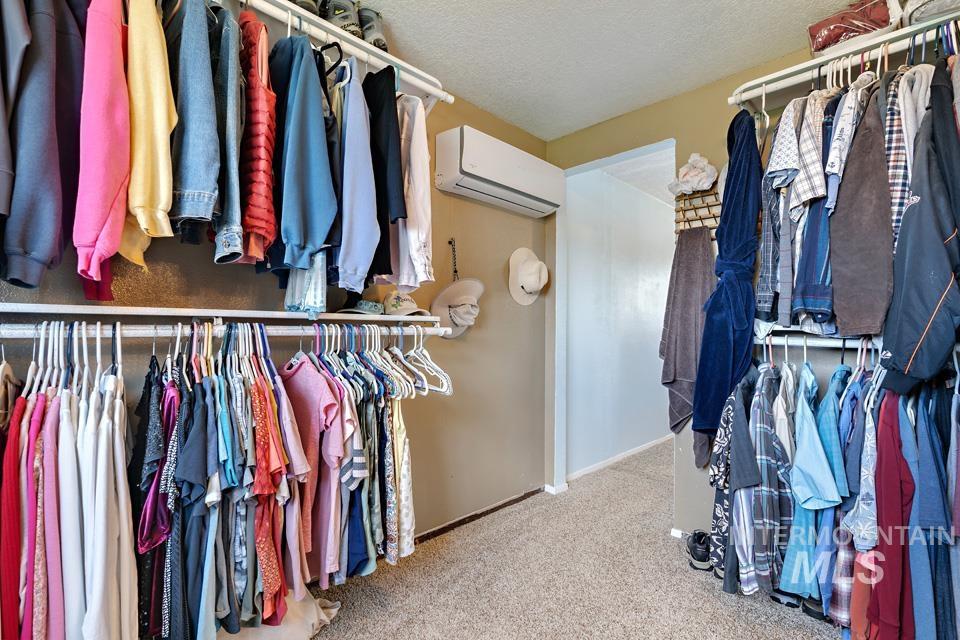 Walk in closet with an AC wall unit and carpet flooring