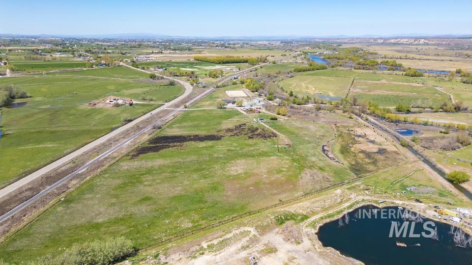 Aerial view of property and surrounding area featuring rural landscape and a nearby body of water