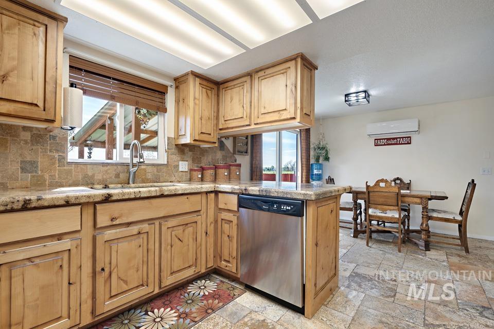 Kitchen featuring dishwasher, plenty of natural light, tasteful backsplash, and stone tile floors