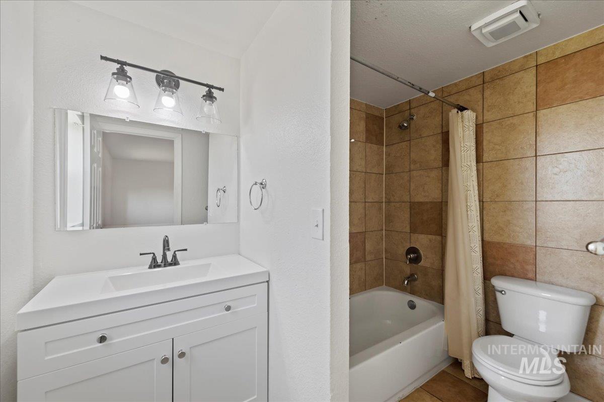 Full bathroom with vanity, shower / tub combo, and tile floors.