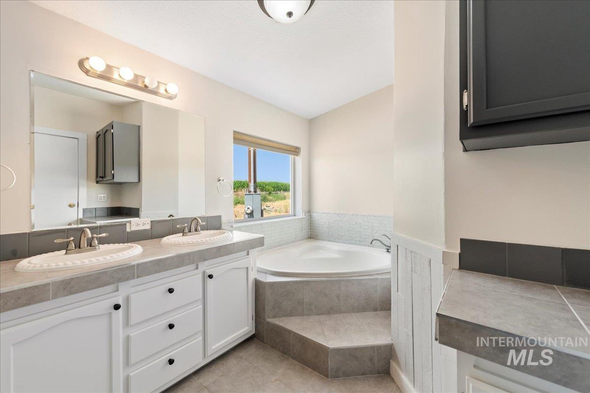 Bathroom featuring double vanity, a bath, and tile flooring