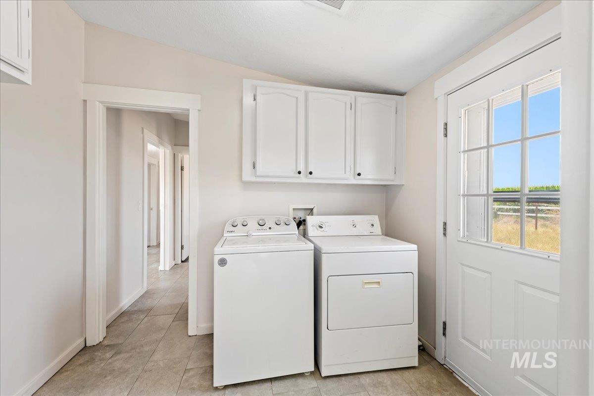 Laundry area featuring independent washer and dryer, cabinet space, and tile floors