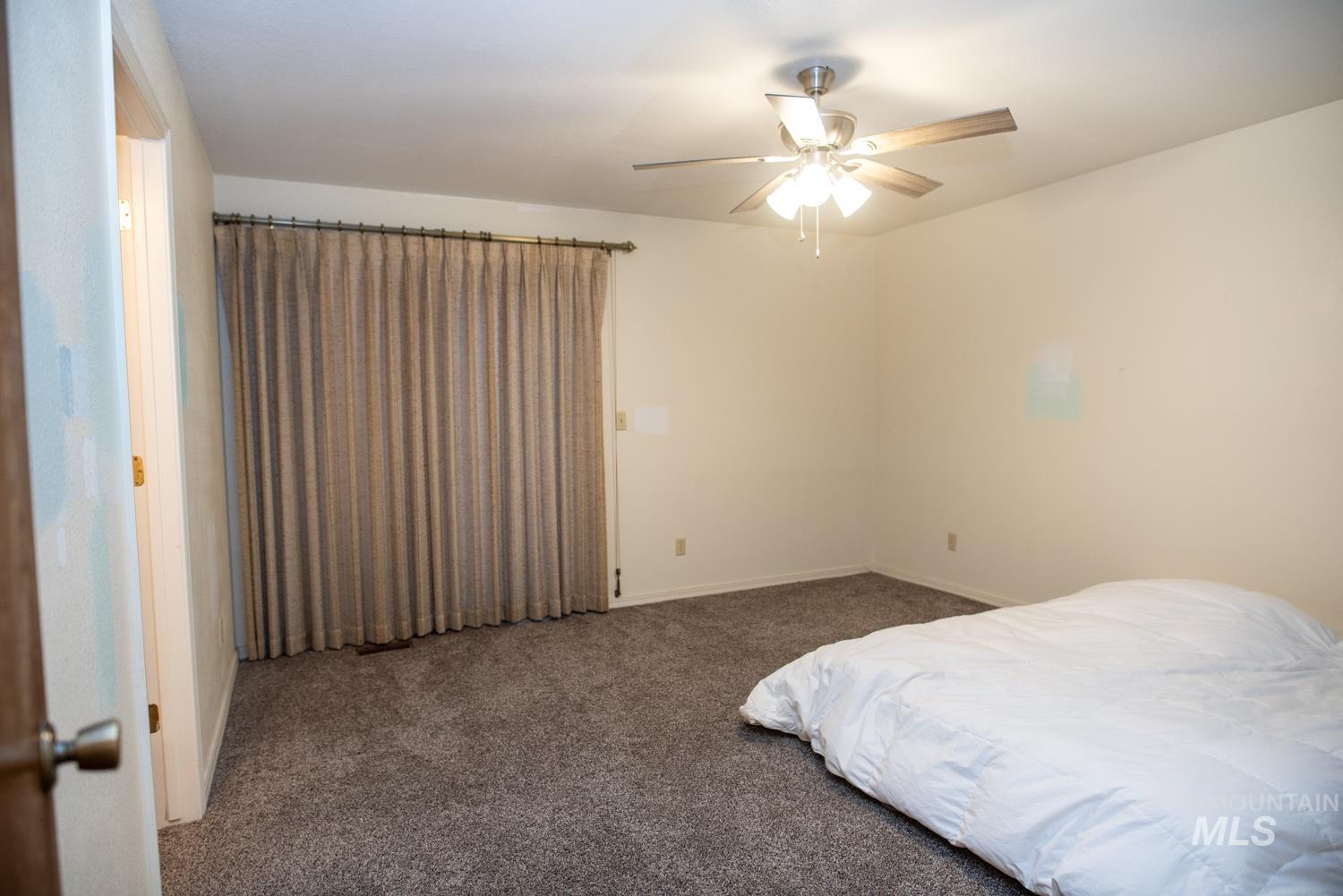 Carpeted bedroom featuring ceiling fan and baseboards