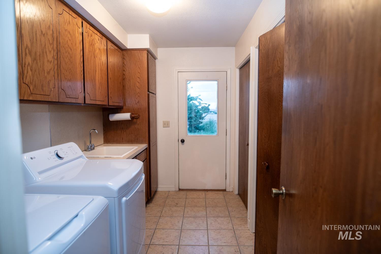 Laundry area featuring light tile patterned floors, cabinet space, and separate washer and dryer