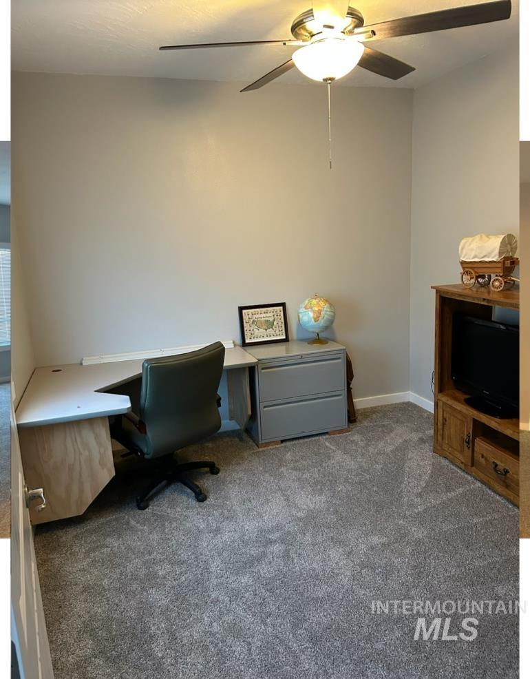 Office area featuring dark colored carpet and ceiling fan