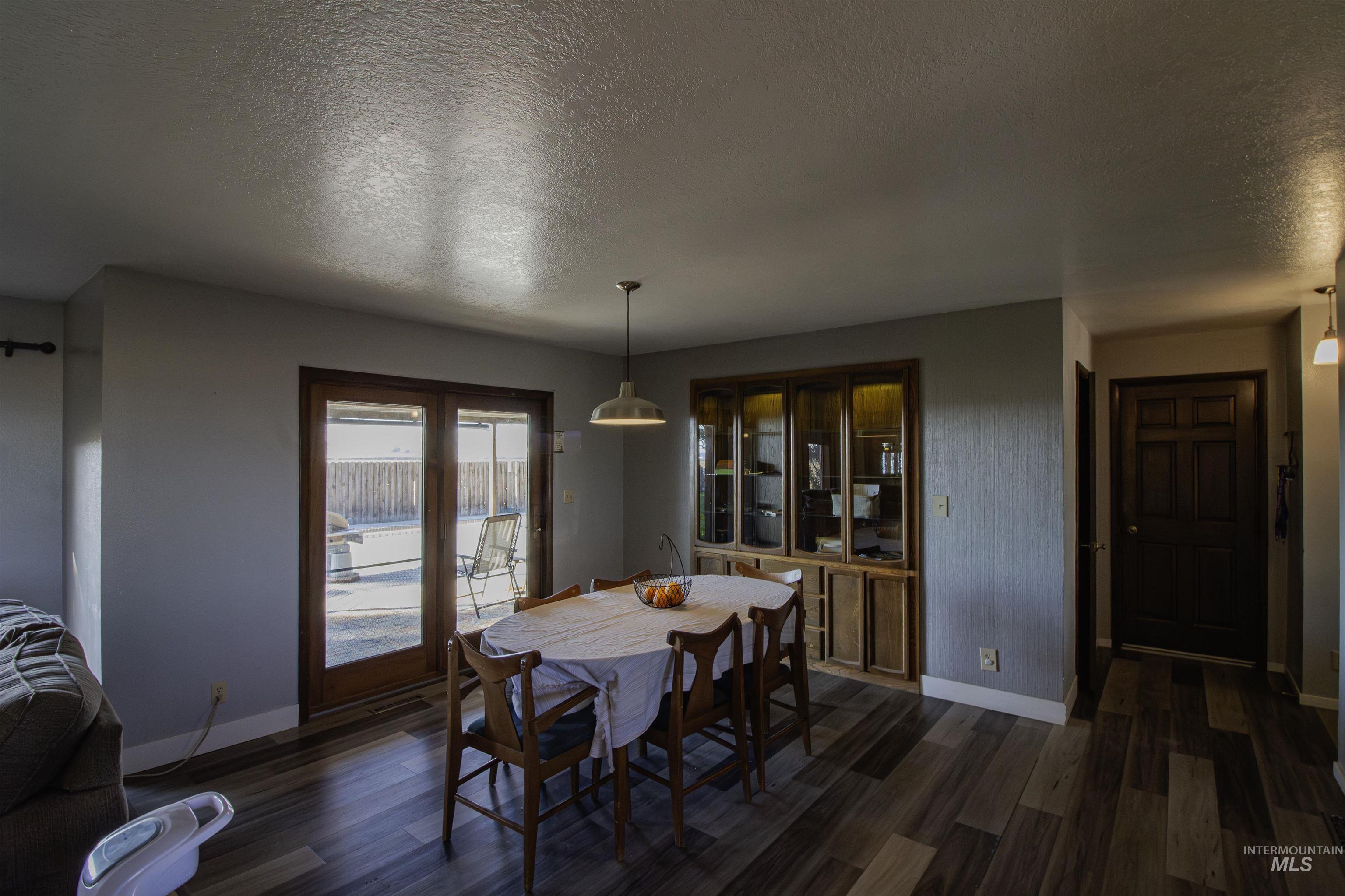 Dining area with a textured ceiling and dark wood-style flooring
