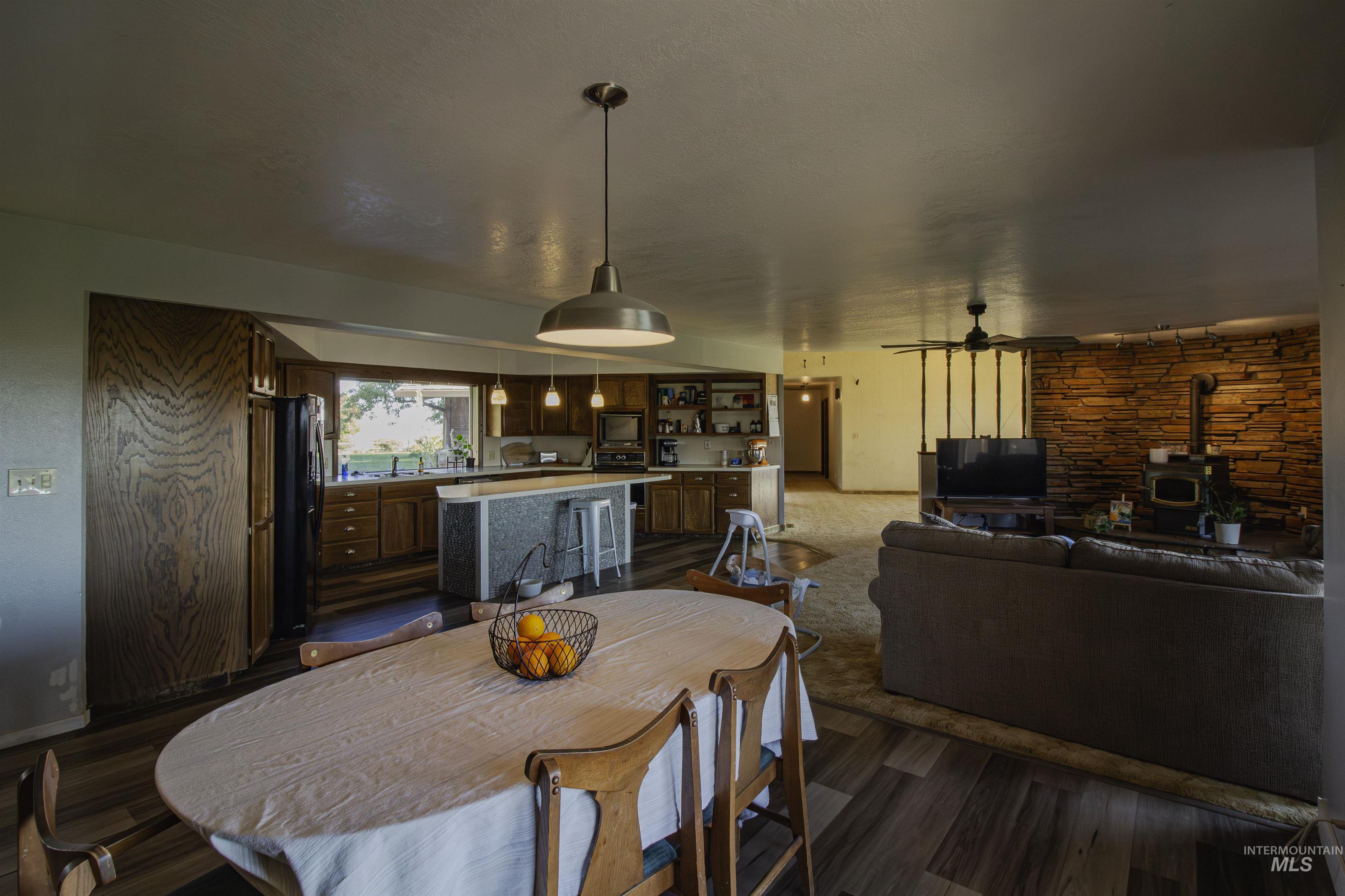 Dining room featuring a wood stove, ceiling fan, and dark wood-type flooring