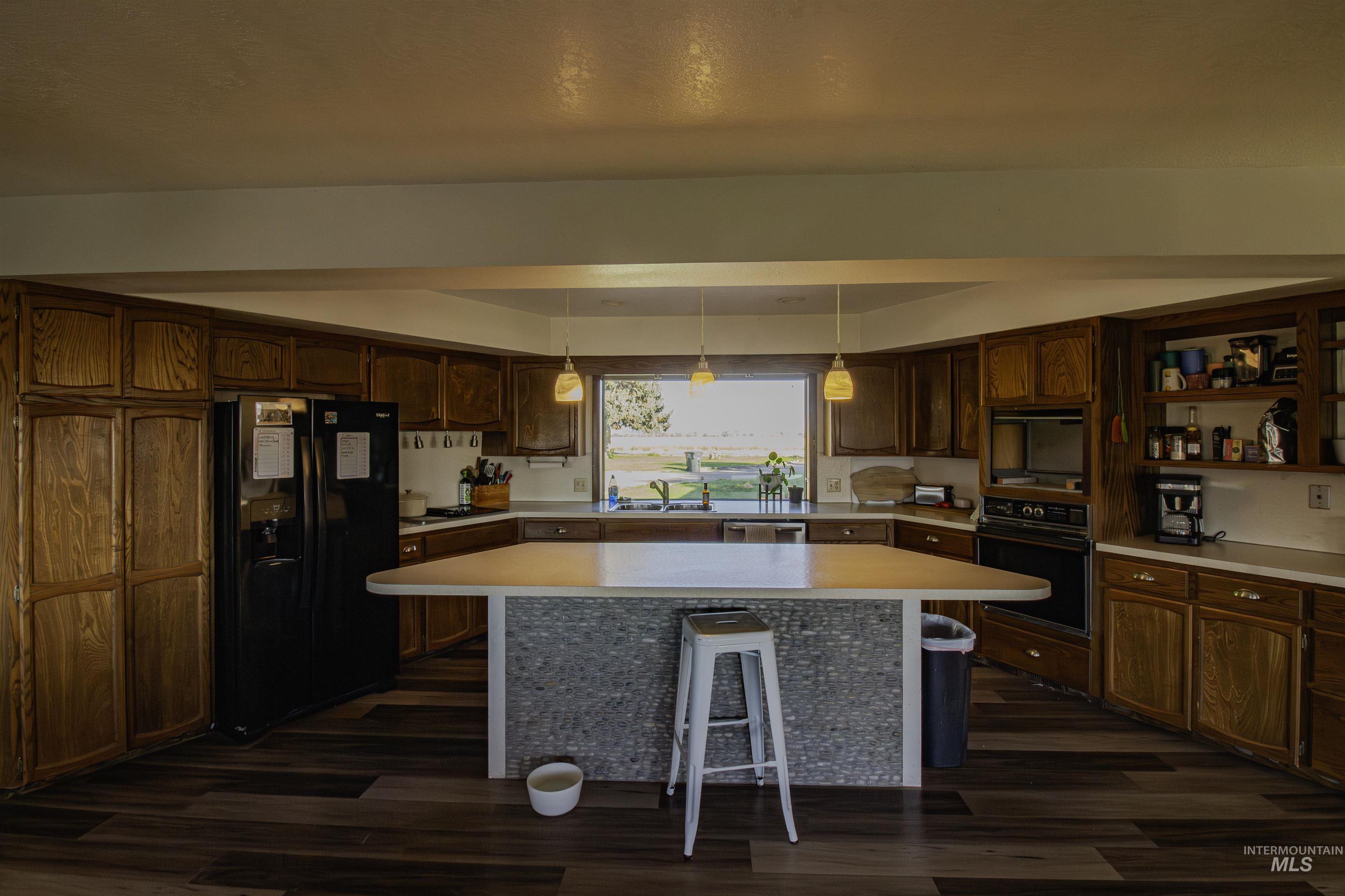 Kitchen with black appliances, a breakfast bar, light countertops, and a kitchen island