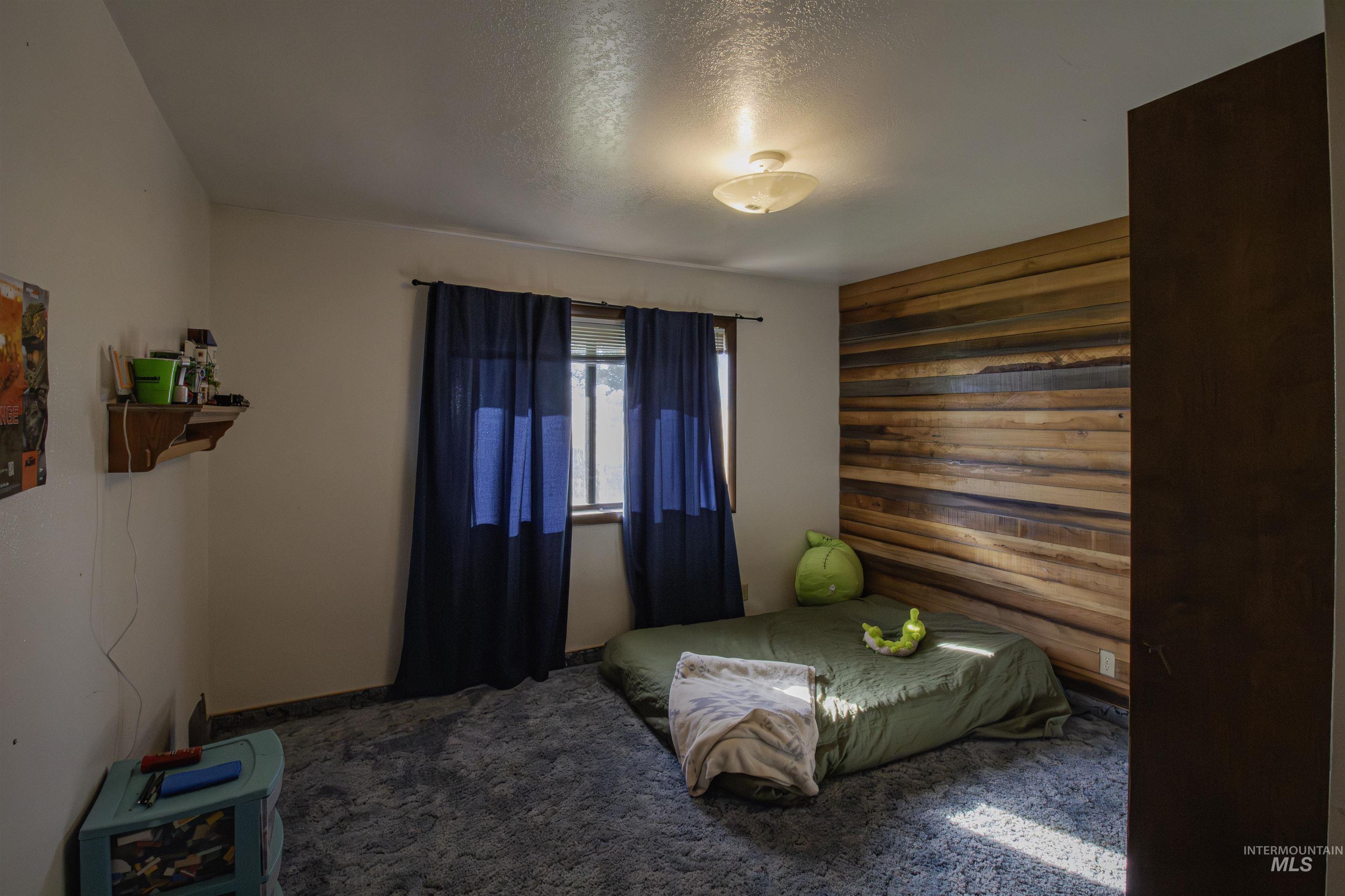 Carpeted bedroom with a textured ceiling and wooden walls
