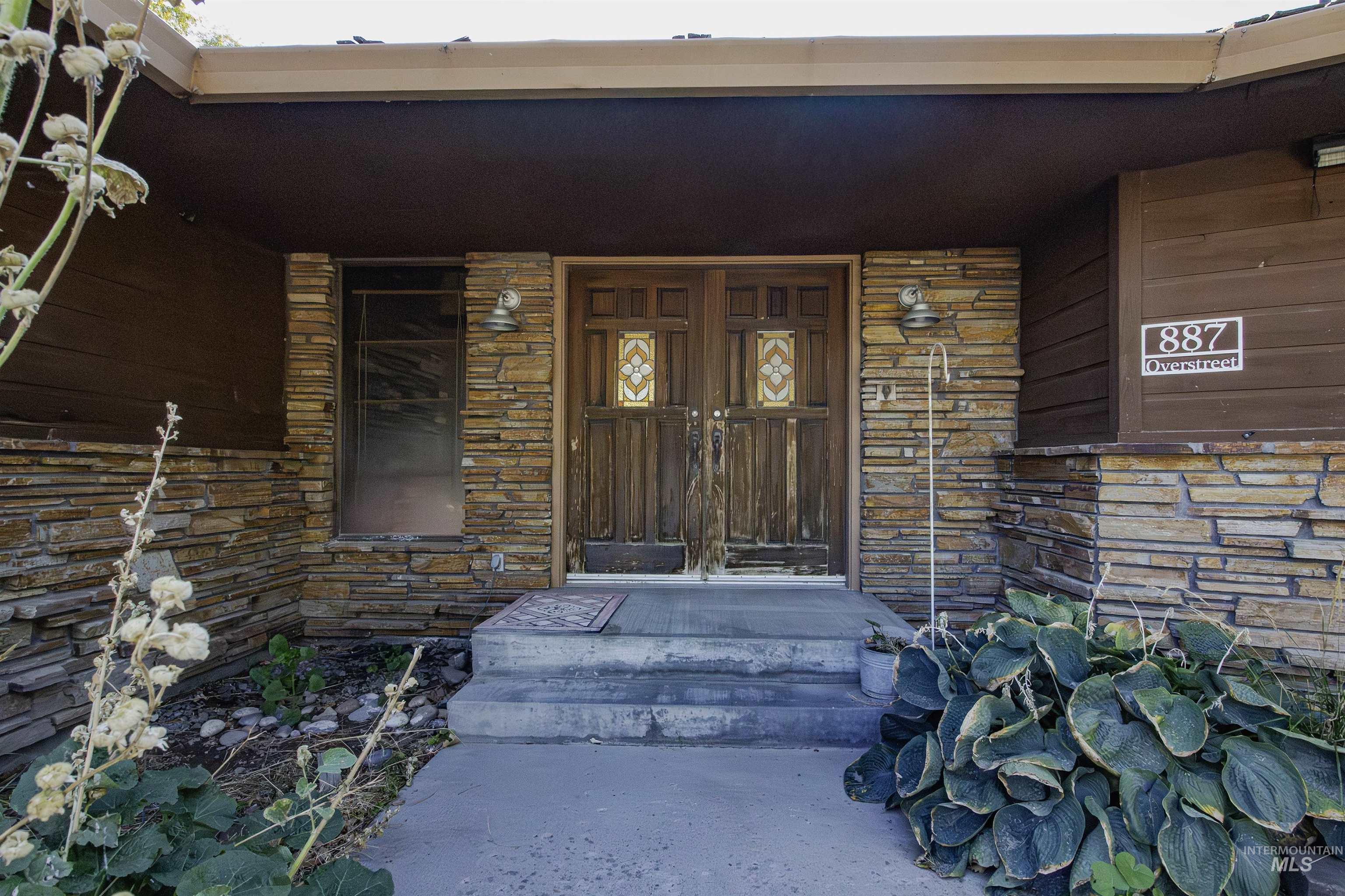 Property entrance featuring stone siding and covered porch