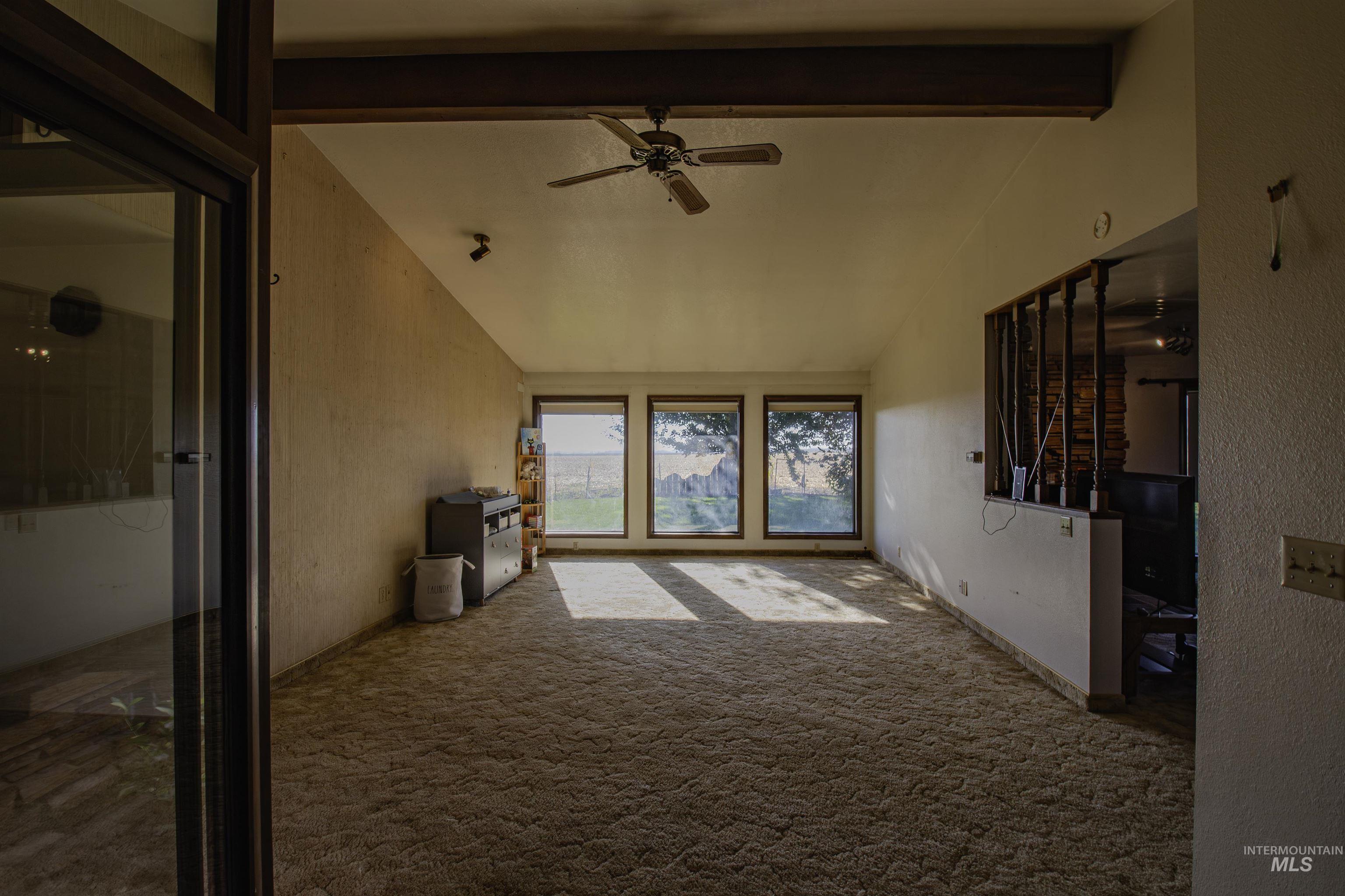 Unfurnished living room featuring carpet flooring, ceiling fan, and a textured wall
