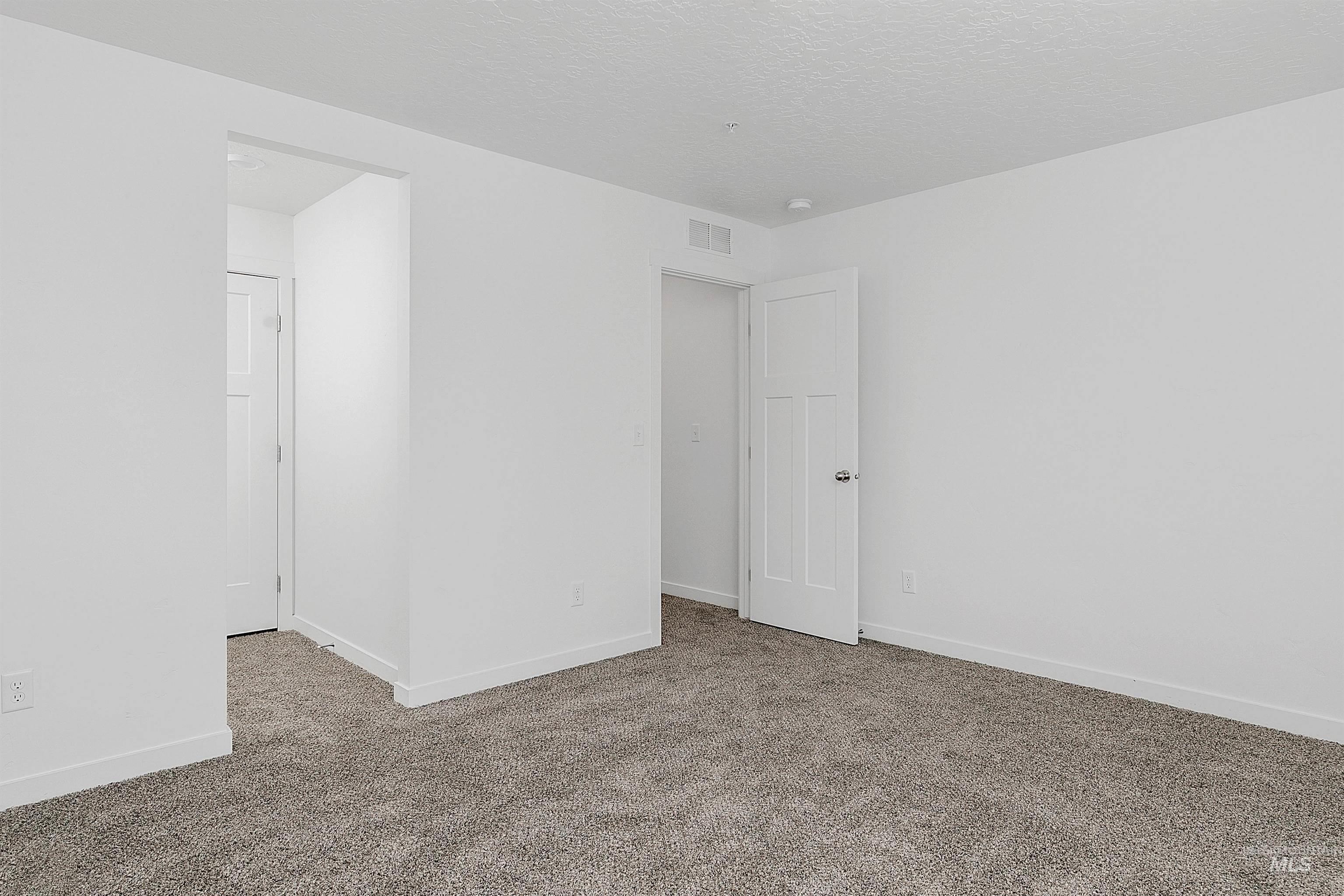 Carpeted empty room featuring baseboards and a textured ceiling