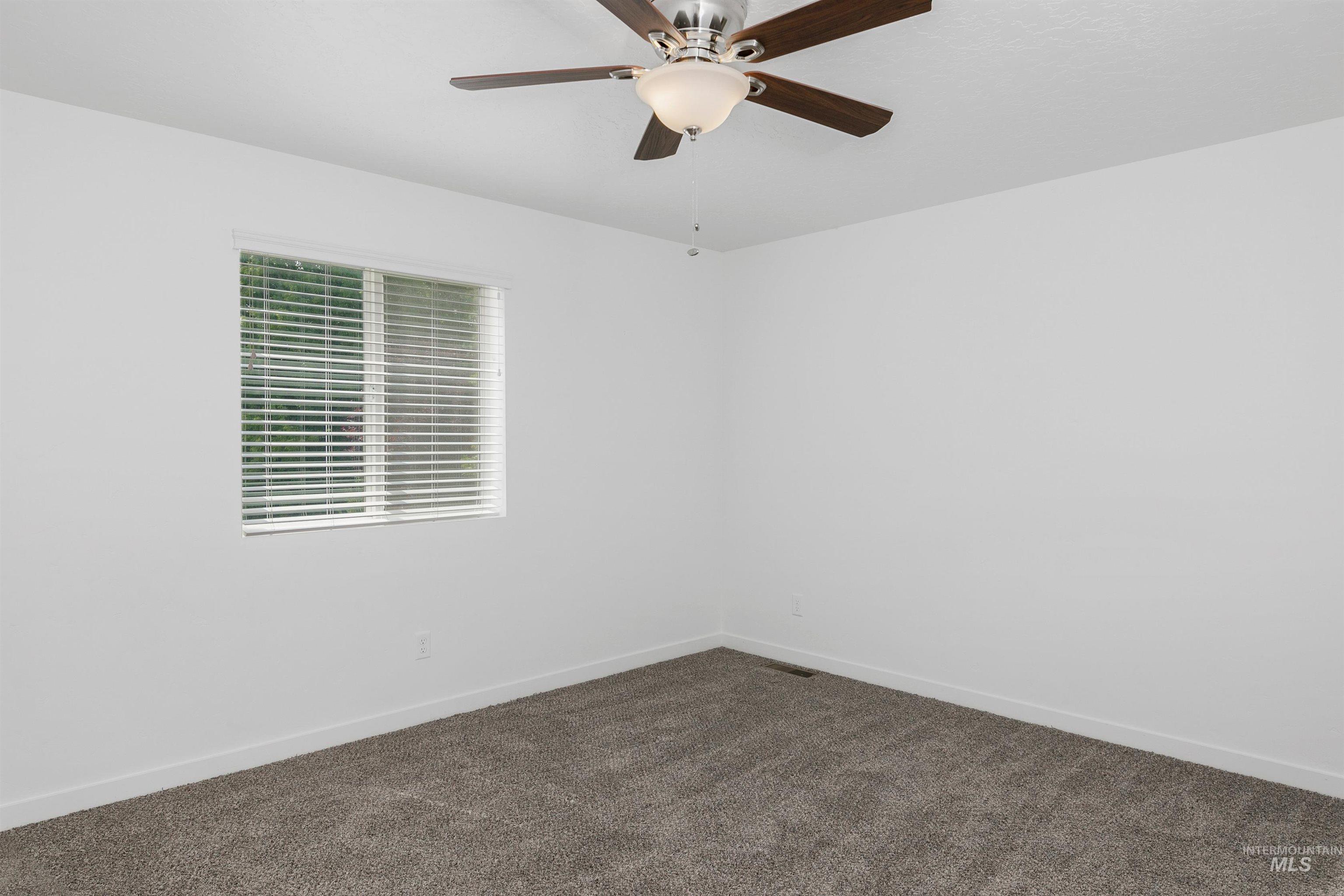 Spare room featuring dark carpet and ceiling fan