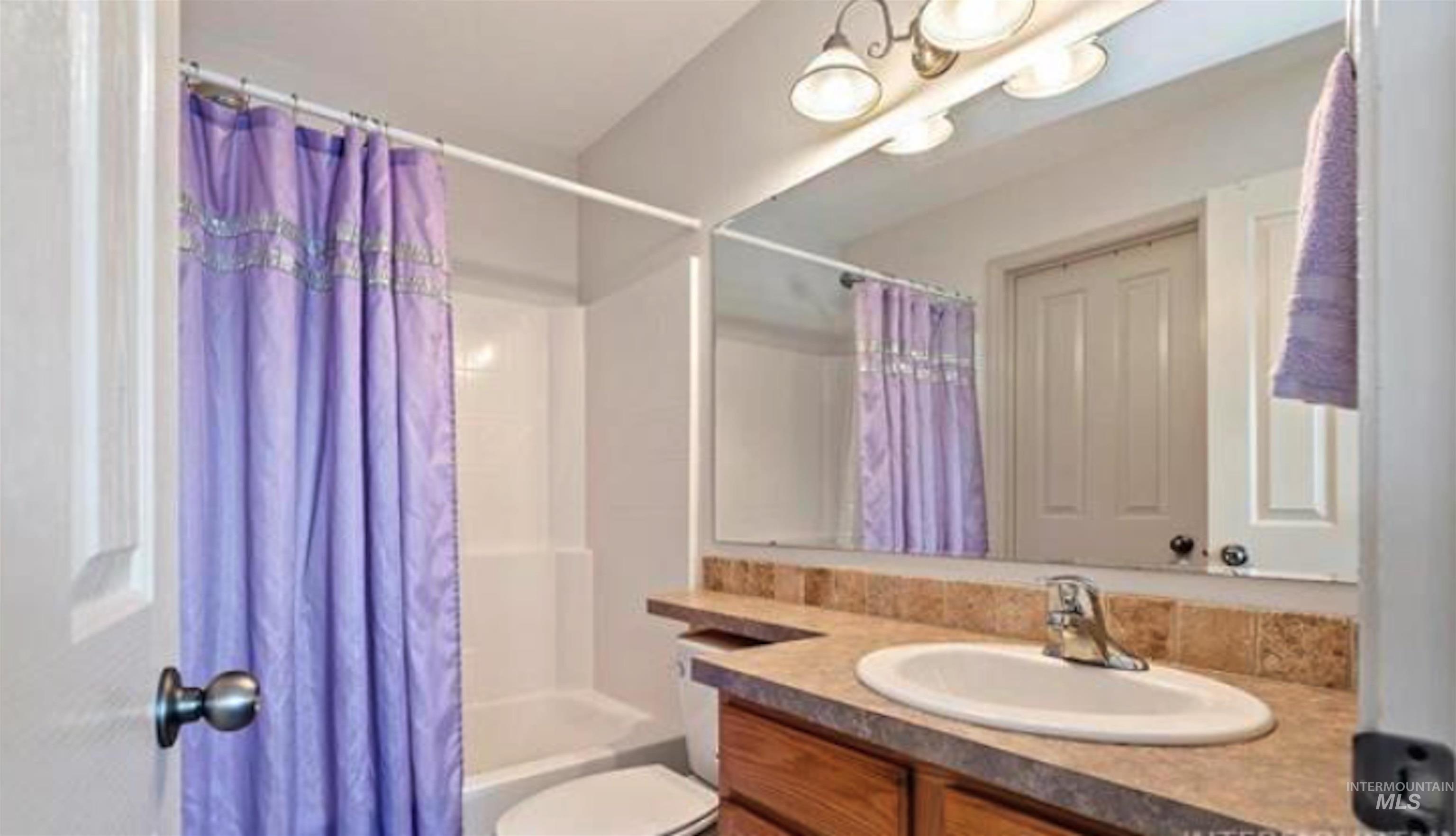 Bathroom featuring vanity, shower / tub combo, and a chandelier