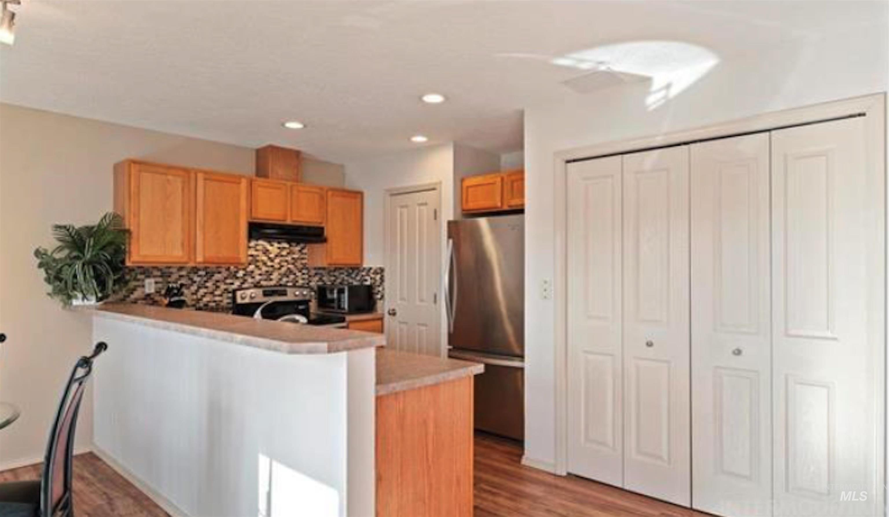 Kitchen with stainless steel appliances, tasteful backsplash, light countertops, a peninsula, and light wood-style flooring