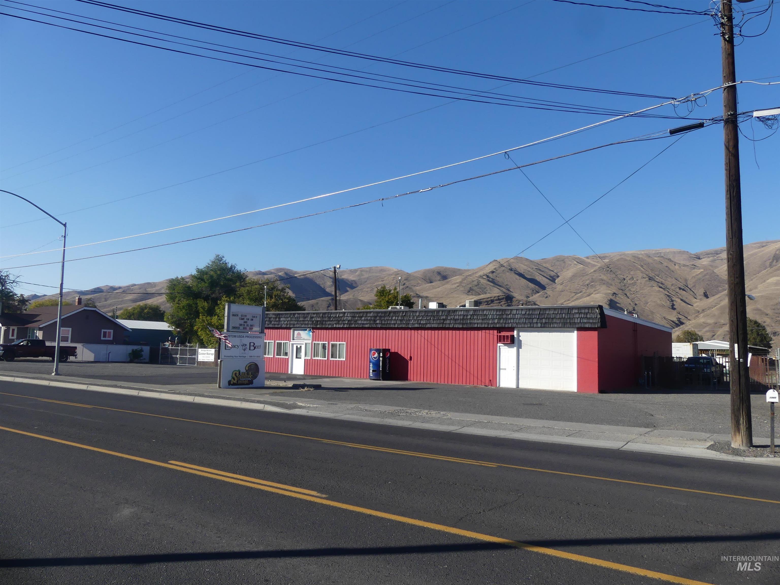 View of asphalt road with a mountain view, street lighting, sidewalks, and curbs