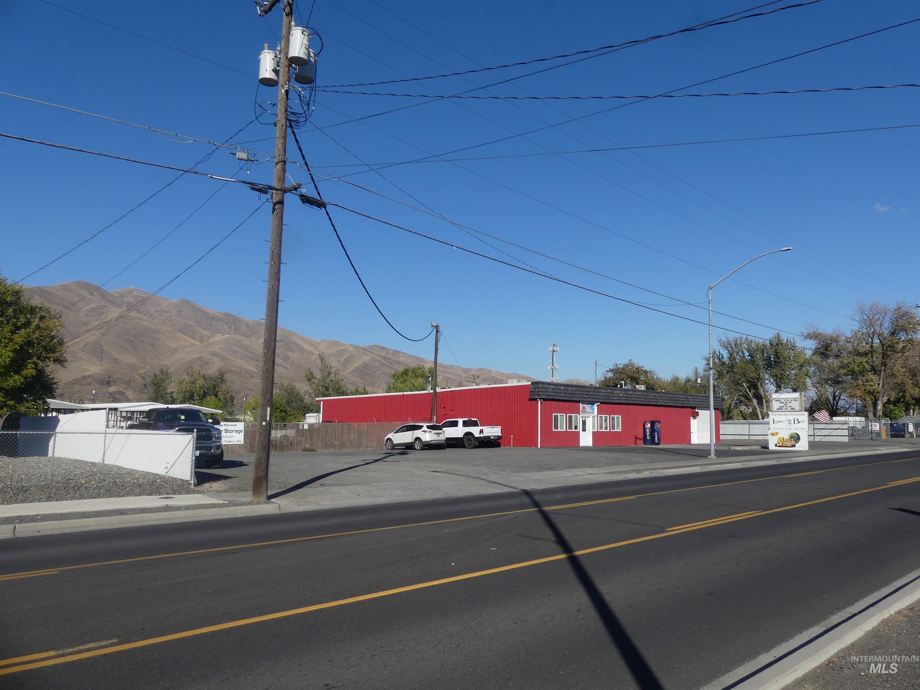 View of asphalt road with sidewalks, street lighting, a mountain view, and curbs