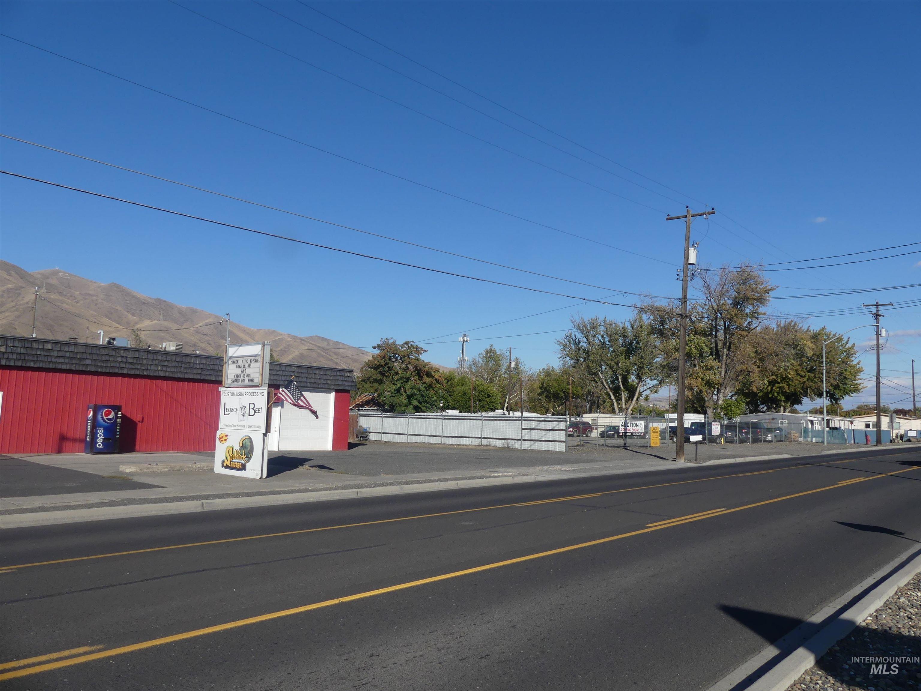 View of asphalt road featuring sidewalks, a mountain view, and curbs