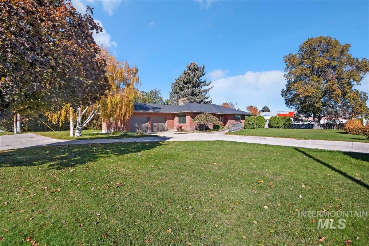 Ranch-style house with driveway, a front yard, a garage, and a chimney