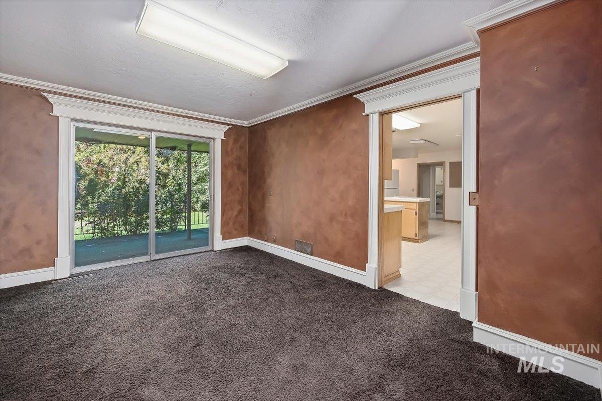 Spare room with crown molding, dark colored carpet, and a textured ceiling