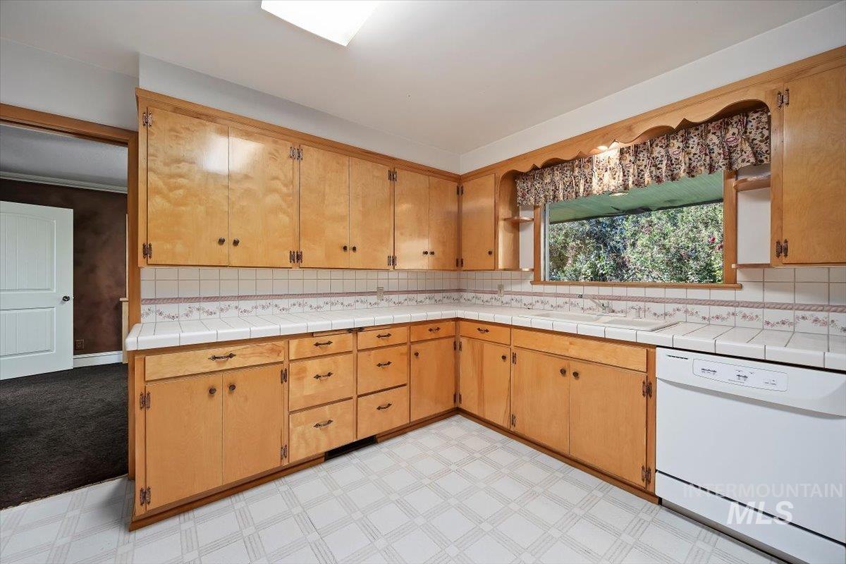 Kitchen with dishwasher, light floors, and backsplash