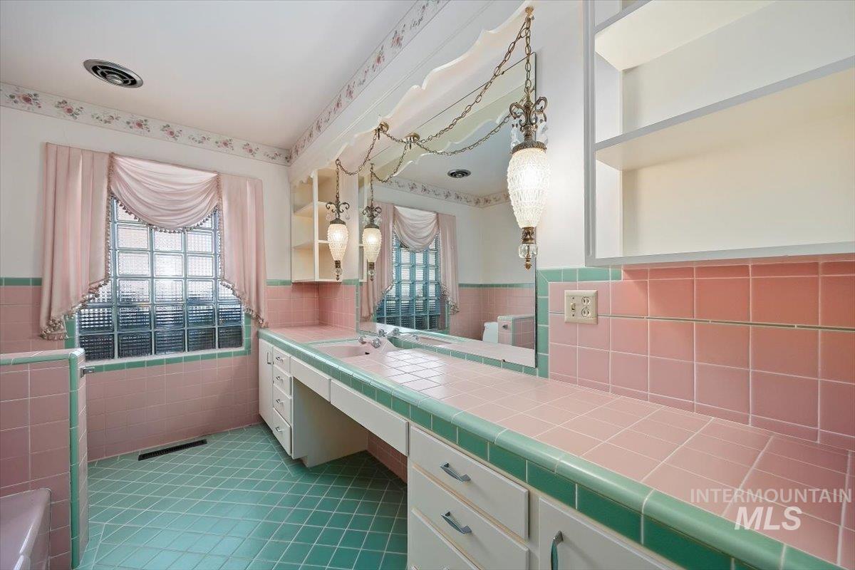 Bathroom featuring vanity, dark tile patterned floors, tile walls, and wainscoting