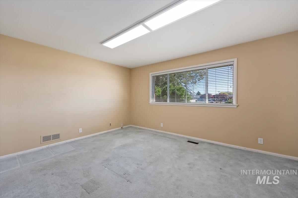 Carpeted spare room featuring baseboards