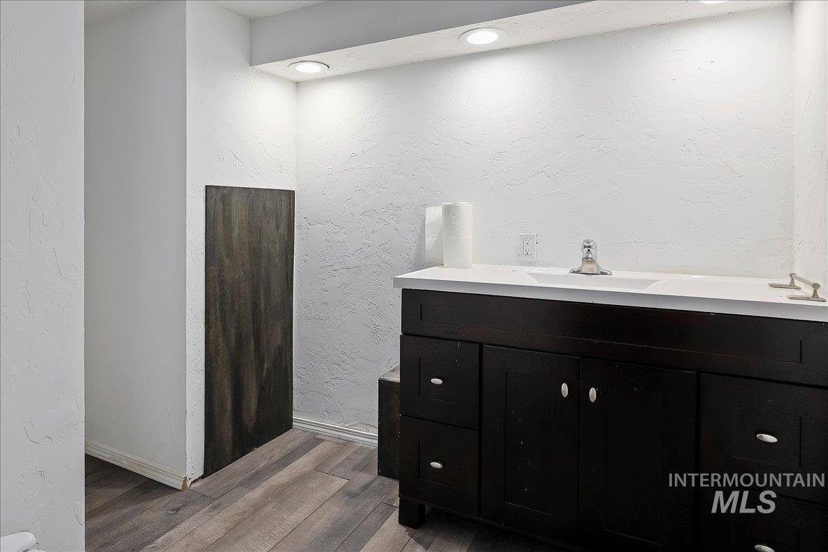 Bathroom featuring a textured wall, vanity, light wood-style flooring, and recessed lighting
